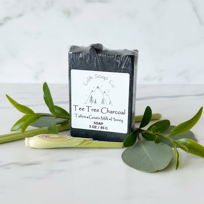 Bar of soap with a label on a marble surface with green leaves