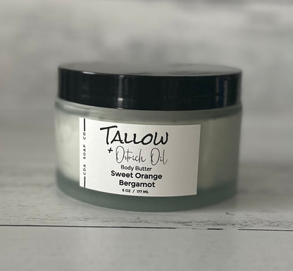 Jar of Tallow + Ostrich Oil sweet orange bergamot body butter with a label on a gray background