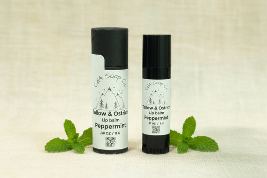 Two lip balm containers from CDA Soap Co on a off white background with peppermint accents 