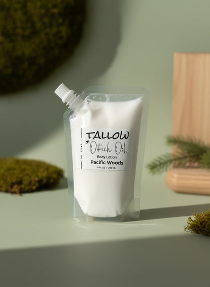 White body lotion pouch labeled 'Tallow' on a light surface with greenery in the background