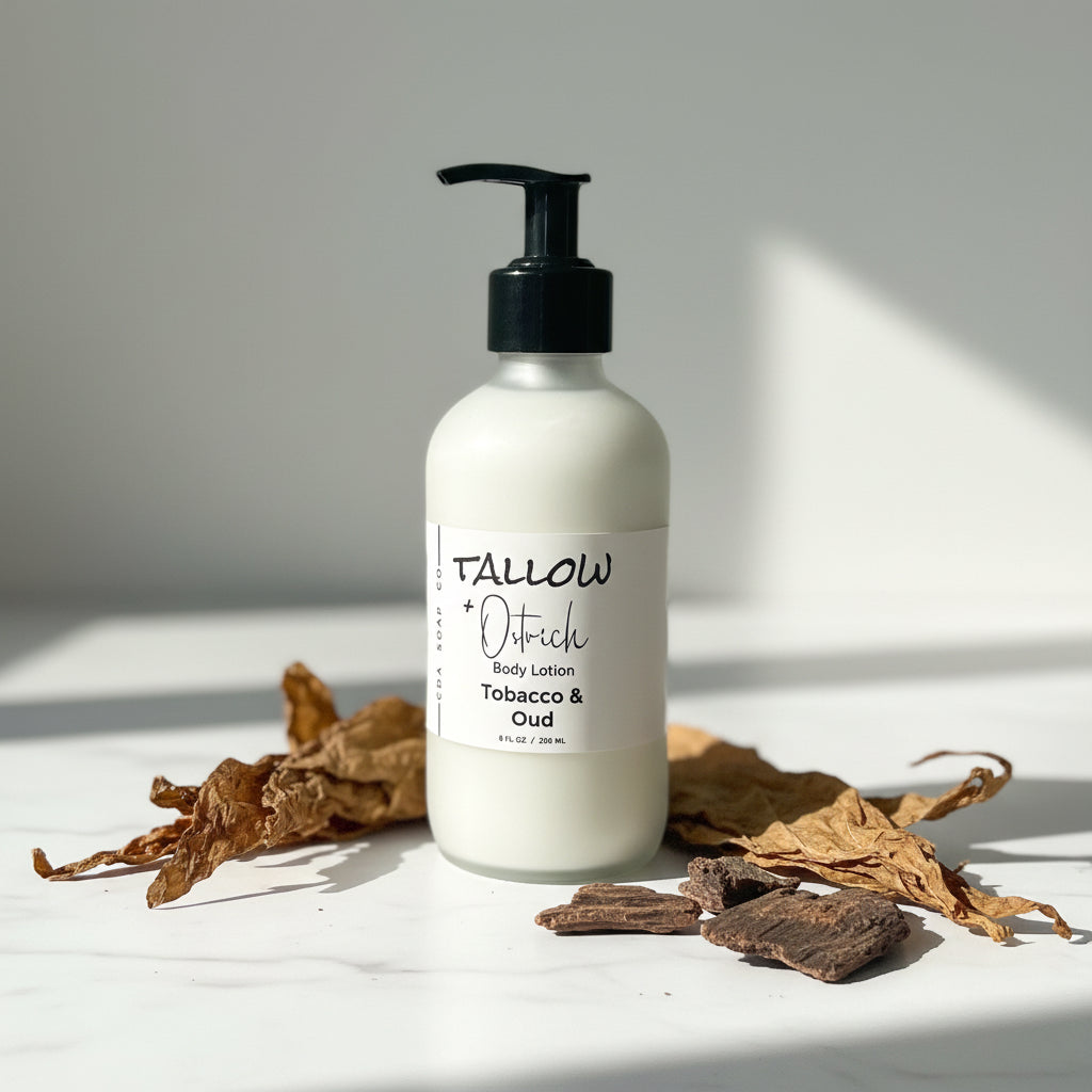 Body lotion bottle labeled 'Tobacco & Oud' on a light surface with dried leaves and tobacco.