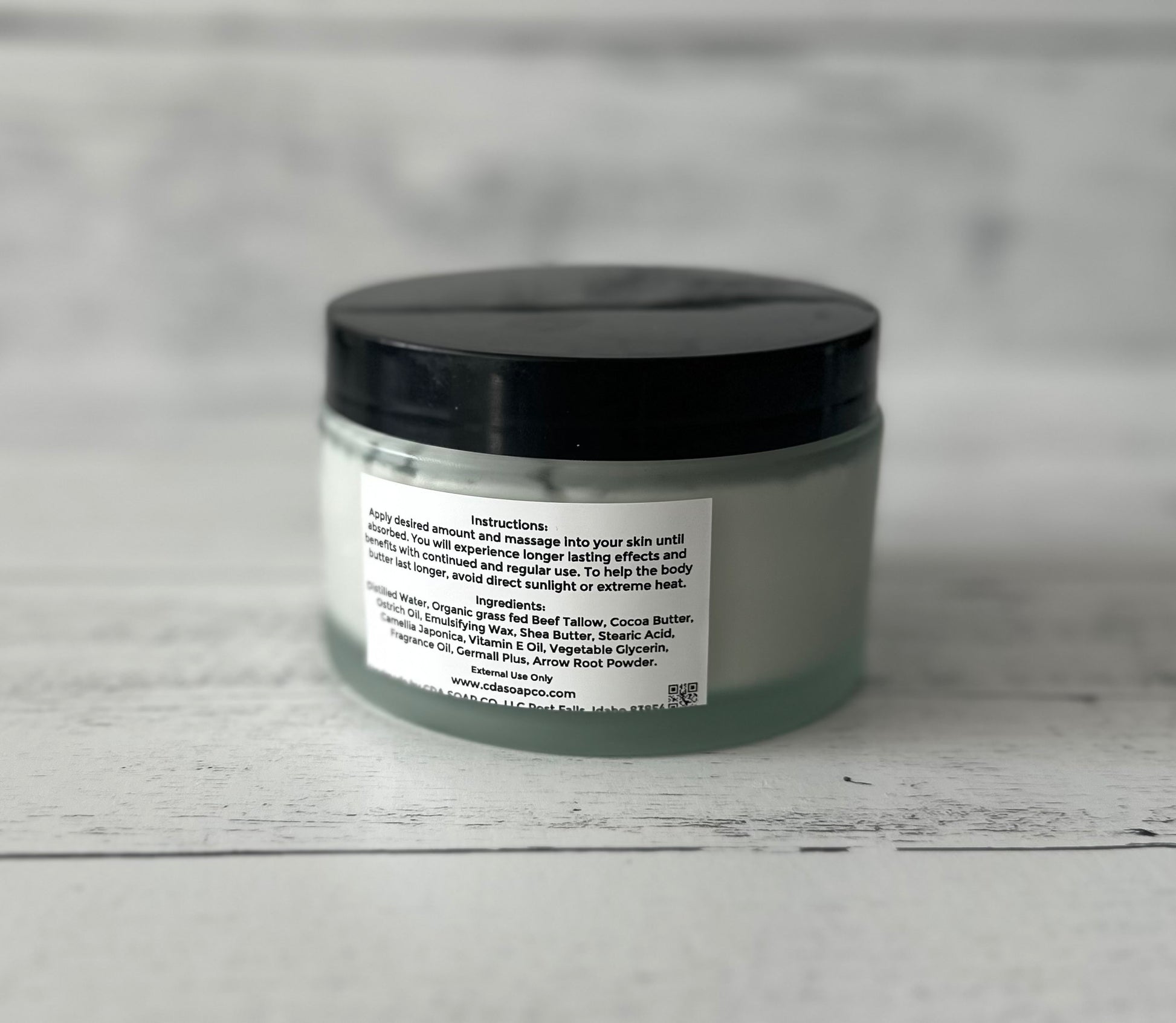 Jar of body butter with a black lid on a gray background