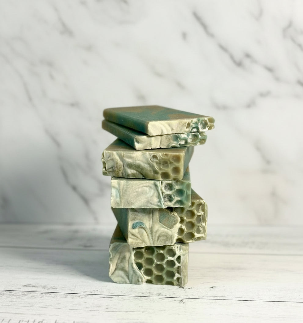 Stack of green and white marbled soap bars on a light marble surface