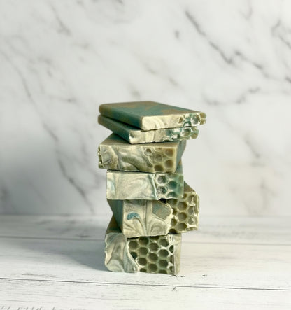 Stack of green and white marbled soap bars on a light marble surface